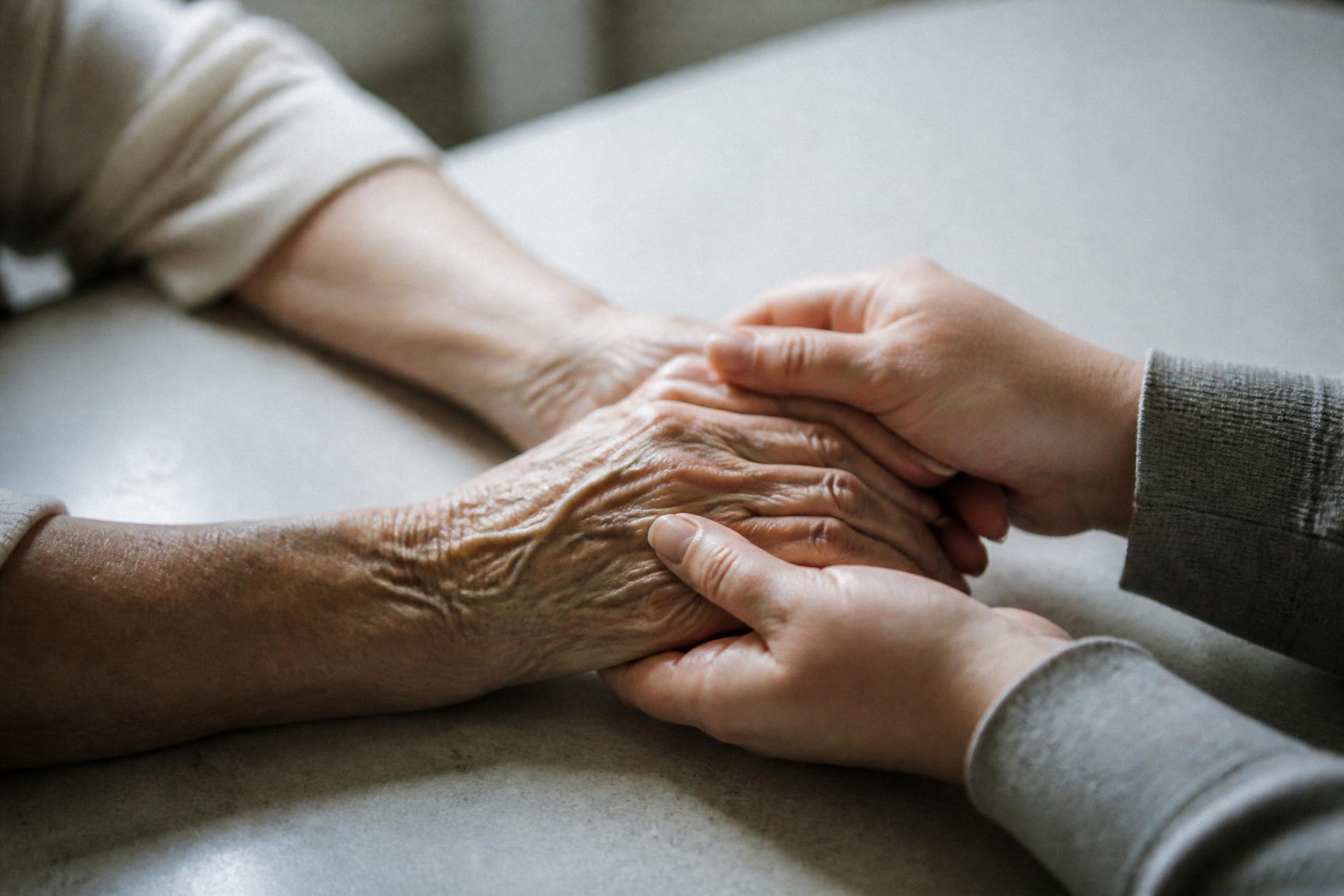 Le mani di una figlia adulta tengono quelle della madre anziana